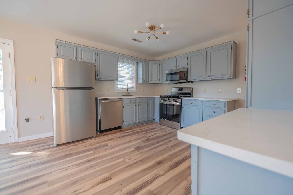 Renovated kitchen with stainless steel appliances, grey cabinetry, and hardwood floors in an SJ Hauck Properties home