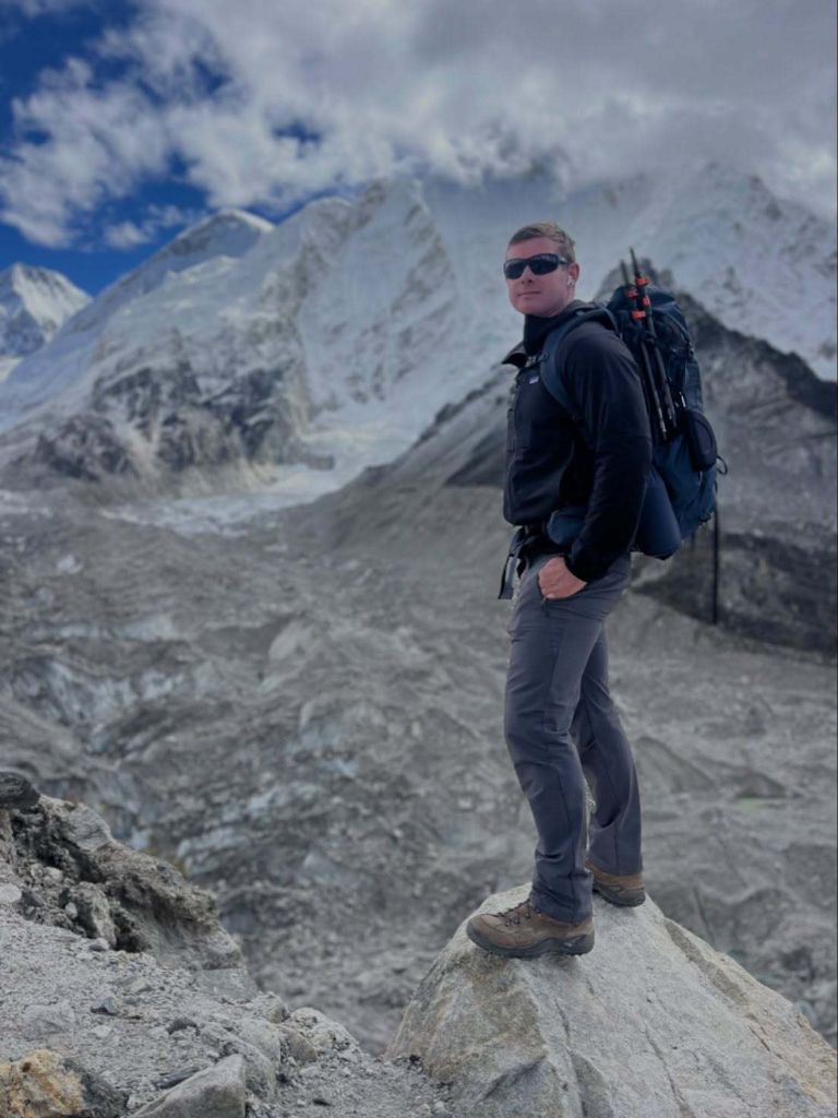 Steven Hauck standing on a rock with snow-capped mountains behind him